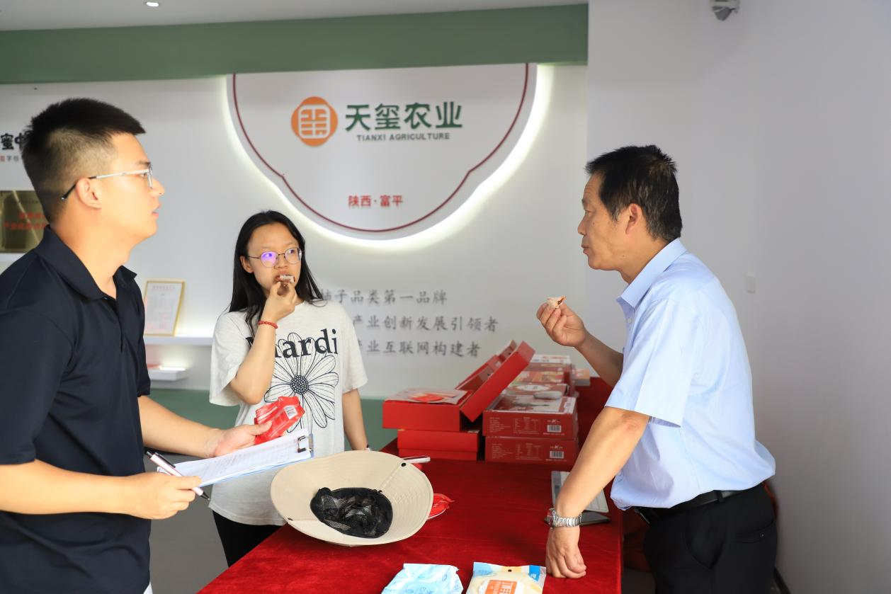 富平大方天玺总经理梁治国(右1)向实践队员王蒙蒙(左1)、李润雨(左2)介绍分发冰柿.png